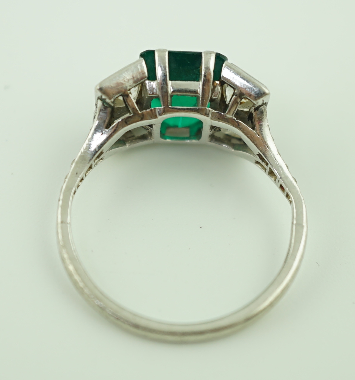 An Art Deco platinum, emerald and square cut diamond dress ring, with diamond chip set shoulders
